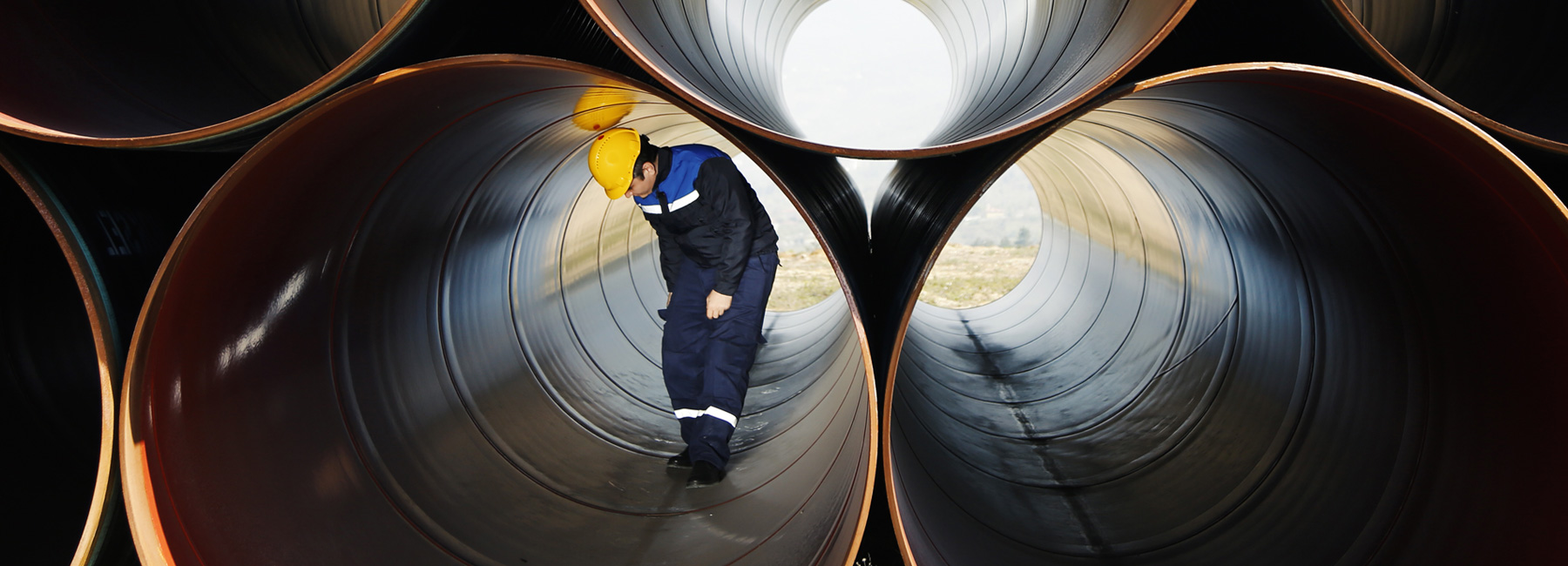 Worker inspecting interior of large pipe, Law Office of John H. Sugden